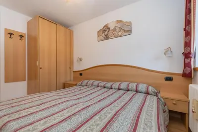 a bedroom with a bed and a wooden headboard at Casa Freina in Vigo di Fassa