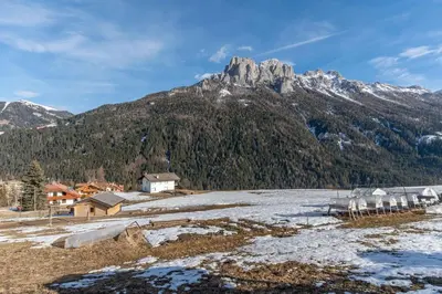 a mountain with a village in the foreground with snow at Casa Freina in Vigo di Fassa