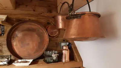 a copper pot and pans hanging on a wall at Chalet-Tabià al Sol montagna Dolomiti Pecol in San Tomaso