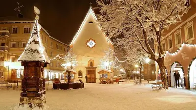 a church with christmas lights in a snowy street at Apartment Cesa Collina Superior in Ortisei