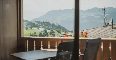a table and chairs looking out a window at a mountain at Ragitt Stodl Ferienwohnungen in Vols am Schlern