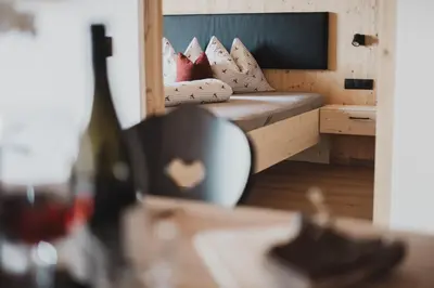 a bedroom with a bed and a bottle of wine at Ragitt Stodl Ferienwohnungen in Vols am Schlern