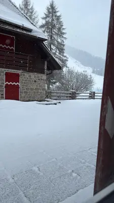 a person standing in the snow in front of a lodge at Golf Hotel & Spa Carezza - Appartamenti Panoramici direttamente sulle piste da sci in Bolzano