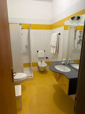 a bathroom with two sinks and a shower and a toilet at Golf Hotel & Spa Carezza - Appartamenti Panoramici direttamente sulle piste da sci in Bolzano