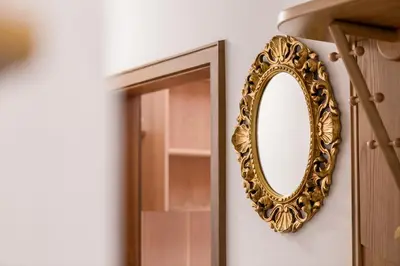 a gold mirror on a wall next to a door at Apartment Sybille in Merano