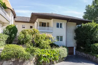 a house with a stone wall and bushes at Apartment Sybille in Merano
