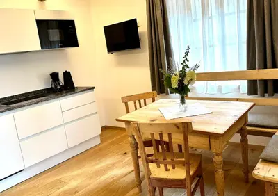 a kitchen and dining room with a wooden table and chairs at Landhaus Breitenberg in Lana