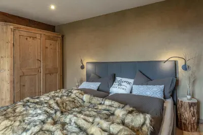 a bedroom with a large bed with a blanket at Chalet Laugenblick Alpine Luxury with Hot Tub and Sauna in Santa Valburga St. Walburg