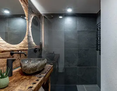 a bathroom with a stone sink and a shower at Chalet Laugenblick Alpine Luxury with Hot Tub and Sauna in Santa Valburga St. Walburg