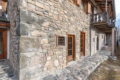 an old stone building with a stone sidewalk next to it at Chalet Lagusello in Alleghe