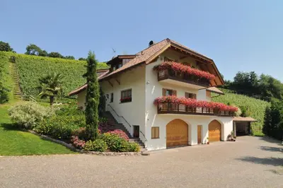 a white house with red flowers on the balcony at Spiegelhof in Appiano sulla Strada del Vino