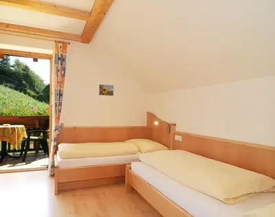 a bedroom with two beds and a balcony with a table at Spiegelhof in Appiano sulla Strada del Vino