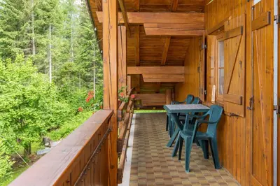 a porch of a log cabin with a table and chairs at Casa Fagher in Canale dʼAgordo