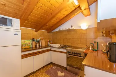 a kitchen with white cabinets and a wooden ceiling at Casa Fagher in Canale dʼAgordo