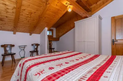 a bedroom with a bed with a red and white bedspread at Casa Fagher in Canale dʼAgordo