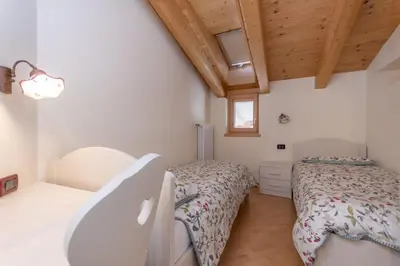 a bedroom with two beds and a wooden ceiling at Casa Milena in Pozza di Fassa