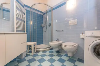 a blue tiled bathroom with a toilet and a shower at Casa Milena in Pozza di Fassa