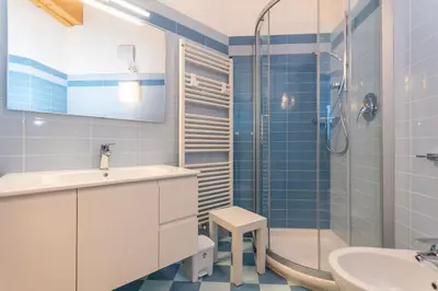 a blue tiled bathroom with a sink and a shower at Casa Milena in Pozza di Fassa