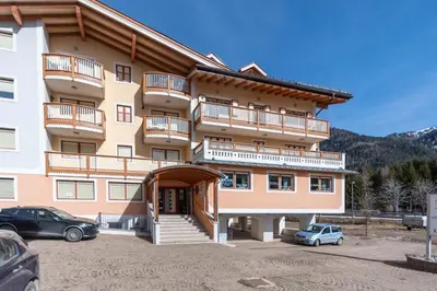 a large building with a car parked in a parking lot at Casa Milena in Pozza di Fassa