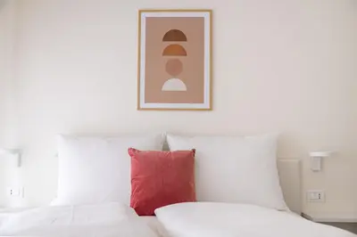 a white bed with a red pillow in a room at Italyescapes Delia in Merano