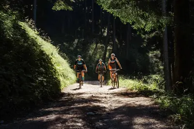 three people riding bikes down a dirt road at Michlhaus nature and suites in Aldino