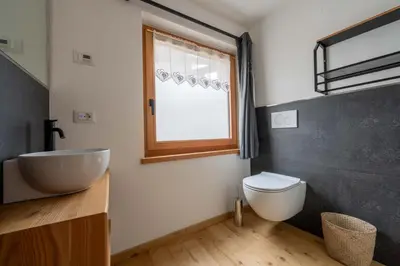 a bathroom with a sink and a toilet and a window at Ciasa Marta in Vigo di Fassa