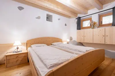 a large bed in a room with wooden cabinets at Ciasa Marta in Vigo di Fassa