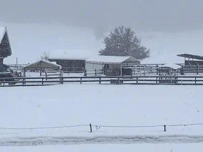 a snow covered field with a fence and a barn at Casa dei sogni in Valdaora