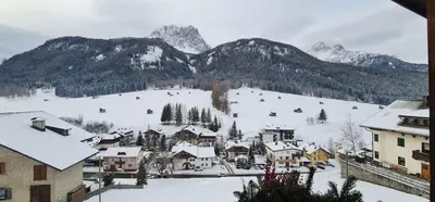 a snow covered village with mountains in the background at Casa dei sogni in Valdaora