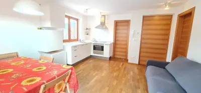 a kitchen and a dining room with a table with a red table cloth at Casa dei sogni in Valdaora