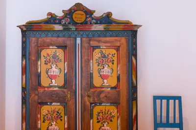 a wooden cabinet against a wall next to a chair at Ciasa Plandros Apartments in La Valle