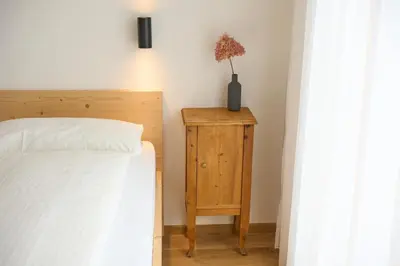 a bedroom with a bed and a table with a vase on it at Ciasa Plandros Apartments in La Valle