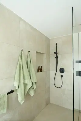 a shower with green towels hanging on a wall at Ciasa Plandros Apartments in La Valle