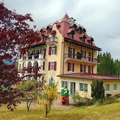 a large yellow building with a red roof at Hotel Regina del Bosco in Ronzone