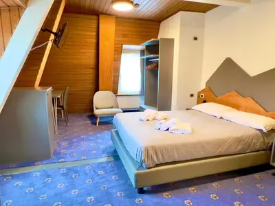 a bedroom with a bed with towels on it at Hotel Regina del Bosco in Ronzone