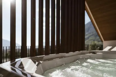 a bath tub with water in it next to a balcony at Apartsuites Rosengarten in Lagundo