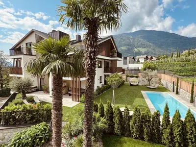 an exterior view of a villa with a swimming pool and palm trees at Apartsuites Rosengarten in Lagundo