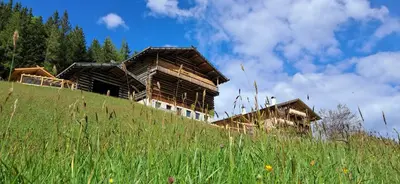 a building on top of a hill with tall grass at Urlaub auf dem Bergbauernhof Gigglhirn in Ulten in Ultimo