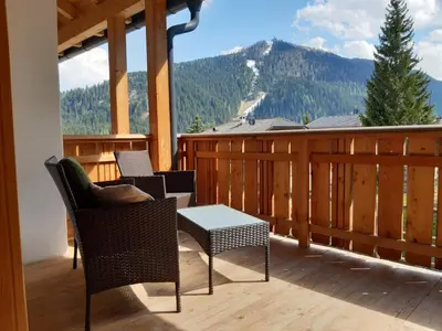 a balcony with chairs and a table and mountains at Raisc - La tua casa in Val Badia in La Villa
