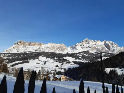 a snow covered mountain with a house in the foreground at Raisc - La tua casa in Val Badia in La Villa