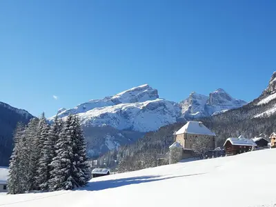a building on a snow covered slope with a mountain at Raisc - La tua casa in Val Badia in La Villa