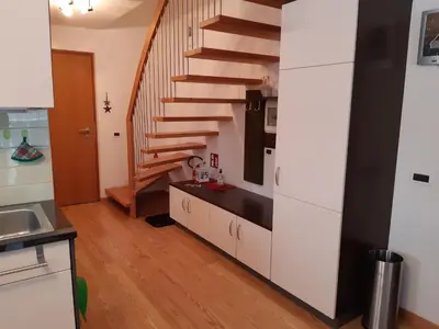 a kitchen with white cabinets and a spiral staircase at Raisc - La tua casa in Val Badia in La Villa
