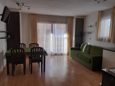 a living room with a green couch and a table and chairs at Raisc - La tua casa in Val Badia in La Villa