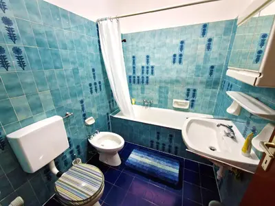 a blue tiled bathroom with a toilet and a sink at Apartment Geranie - Alpstay in Naturno