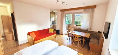 a hotel room with a bed and a desk and a table at Apartment Geranie - Alpstay in Naturno