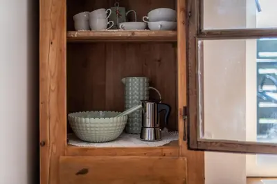 a wooden cabinet with bowls and cups and a pitcher at Appartments DAS Hubertus in Termeno