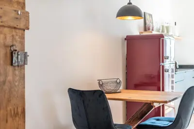 a kitchen with a wooden table and chairs and a refrigerator at Appartments DAS Hubertus in Termeno