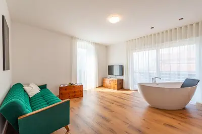 a bathroom with a tub and a couch and a television at Appartments DAS Hubertus in Termeno