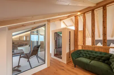 a living room with a green couch and a chair at Appartments DAS Hubertus in Termeno