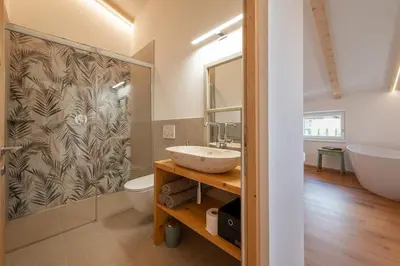 a bathroom with a sink and a tub and a toilet at Appartments DAS Hubertus in Termeno